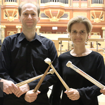 Two musicians (a man and a woman) holding drumsticks in their hands. The pipe organ in the background.