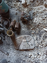 Picture of various objects, including an empty mug, a damaged tile and debris.