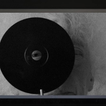 Black and white picture of an elderly woman with gray hair, looking through the hole in a black circle