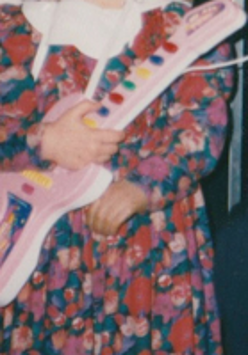 One of the exhibition works: a child, with its face unvisible, holding a toy guitar.