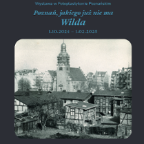 Black and white photo in a black frame: old buildings - houses in the foreground, and a church in the background.