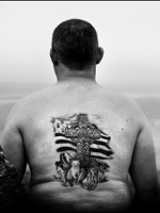 Black and white photo of a man's tattooed back.