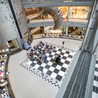 Photo of a hall with a big chess-board painted on the floor.