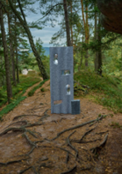 One of the exhibition works: a metal object standing on a path in a forest.