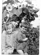 Black and white photo of a young woman and two kids; sunflowers as a background
