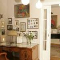 Photo of musical salon - an old-fashioned desk, pictures on the wall, door on the right.