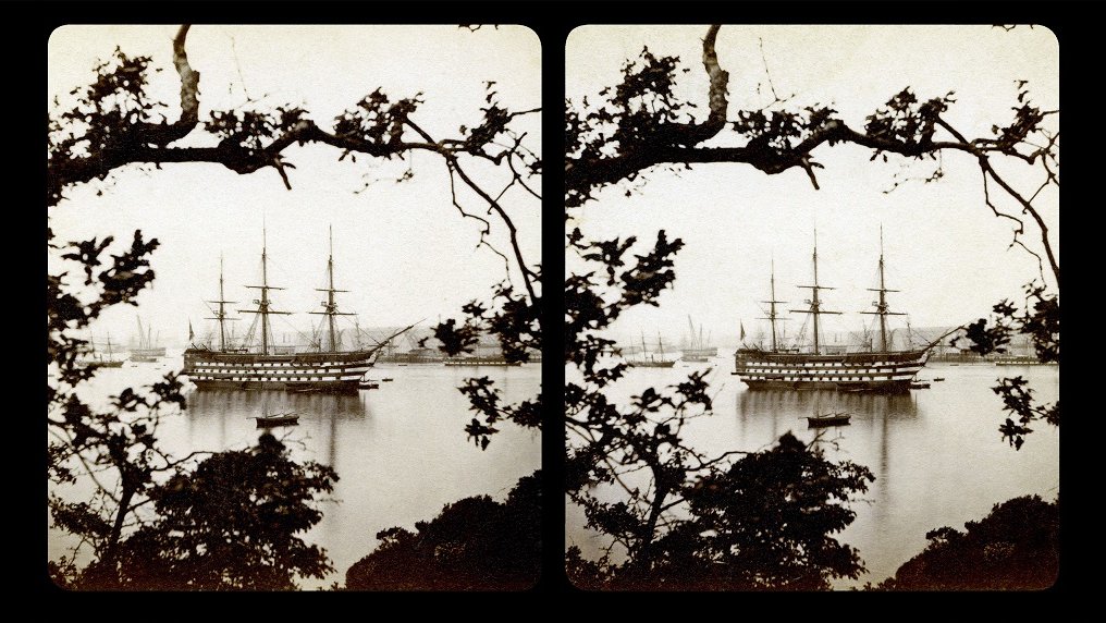 Stereophotograph of a ship with three masts floating on water. In the foreground bushes and a tree branch.