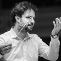 Black and white photo of the conductor Łukasz Borowicz, who is holding a baton in his right hand