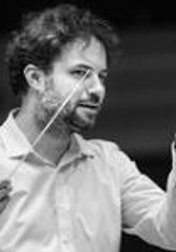 Black and white photo of the conductor Łukasz Borowicz, who is holding a baton in his right hand