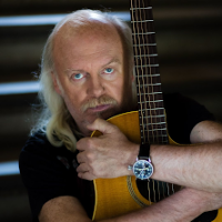 Photo of a man who is hugging a guitar.