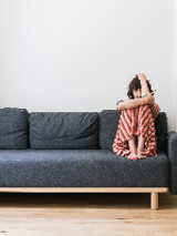 Picture of Katarzyna Groniec, who is sitting with her legs curled up in a couch's corner.