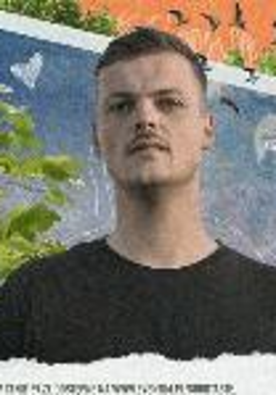 Photo of the vocalist Król. Picture presents young man looking at the camera on a blue, green and orange background