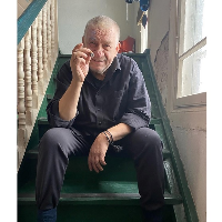 Photo of the artist - a man sitting on stairs wit a cigarette in his hand.
