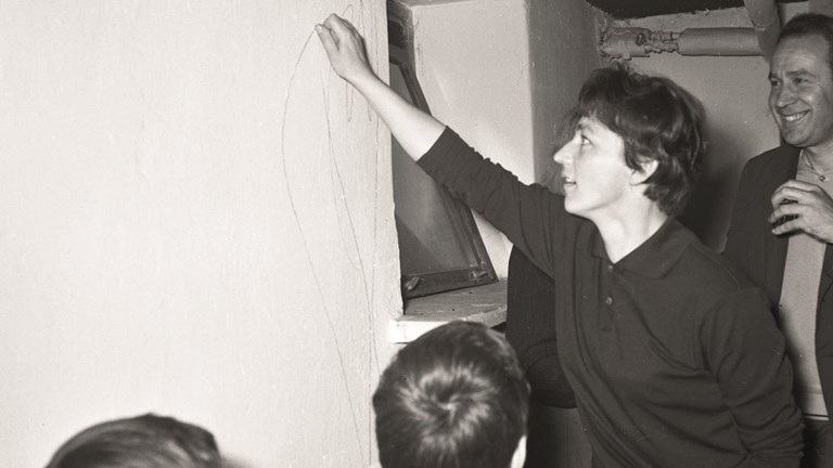 Black and white photo of Magdalena Abakanowicz drawing lines on the wall.