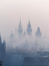 Photo of building roofs and church towers in a fog.