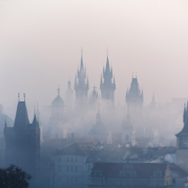 Photo of building roofs and church towers in a fog.
