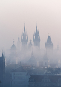 Photo of building roofs and church towers in a fog.