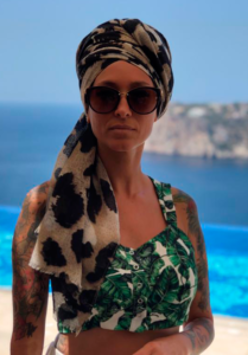 Photo of the singer - a woman in sunglasses; the sea in the background.