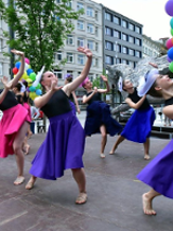 Women in colourful dresses dancing on a street.