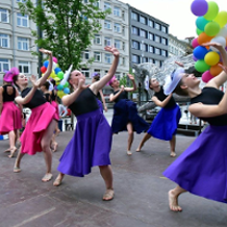 Women in colourful dresses dancing on a street.