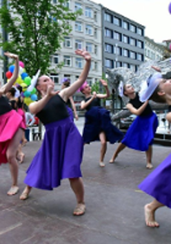 Women in colourful dresses dancing on a street.