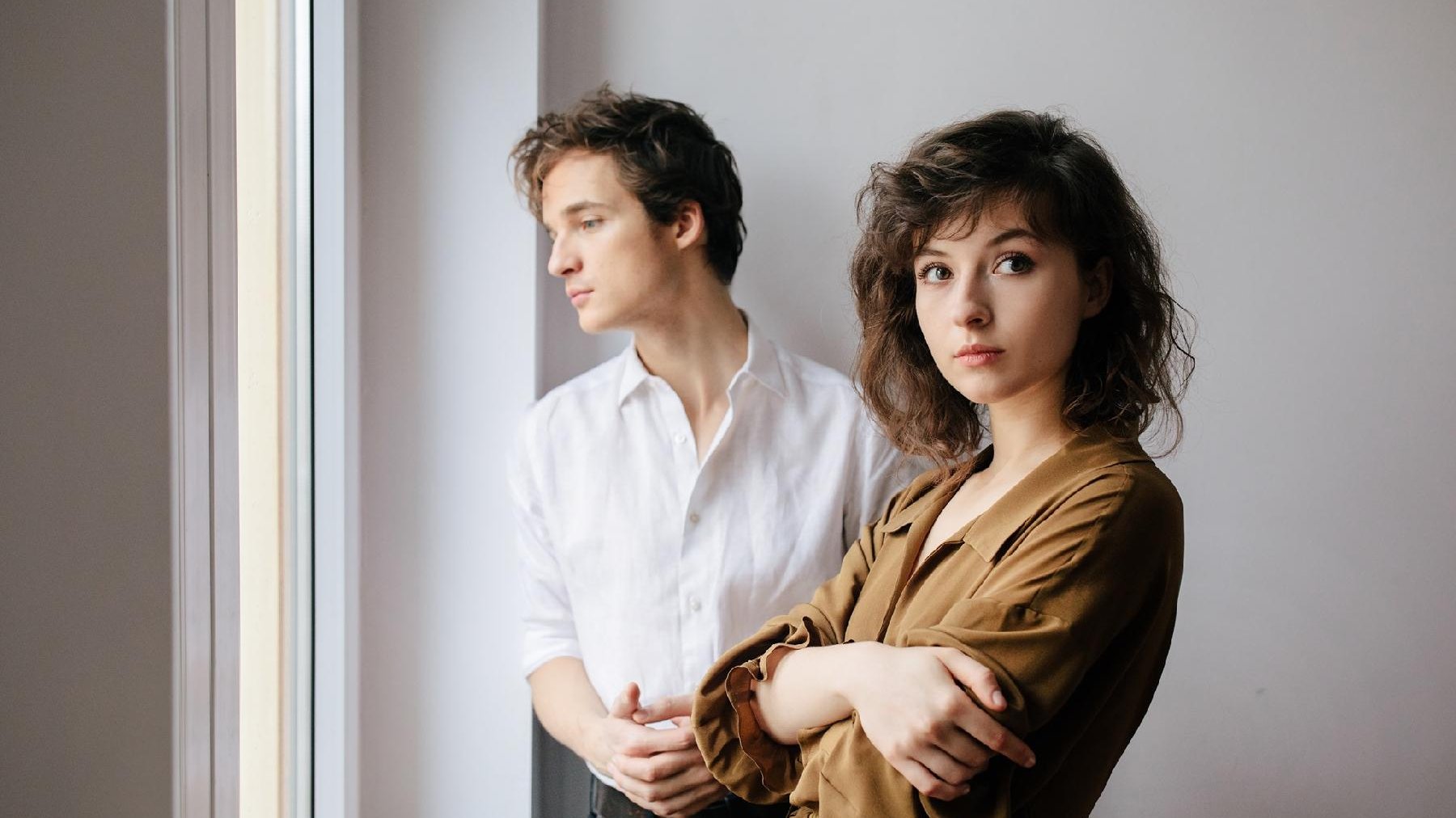 Picture of Kwiat Jabłoni band. A young woman looking at the camera, behind her a man in white shirt looking out of the window