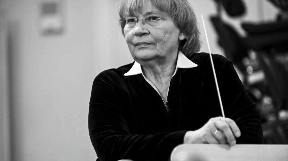 Black and white photo of the conductor Agnieszka Duczmal. The woman is holding a baton in her hand.and looking into the distance - grafika artykułu