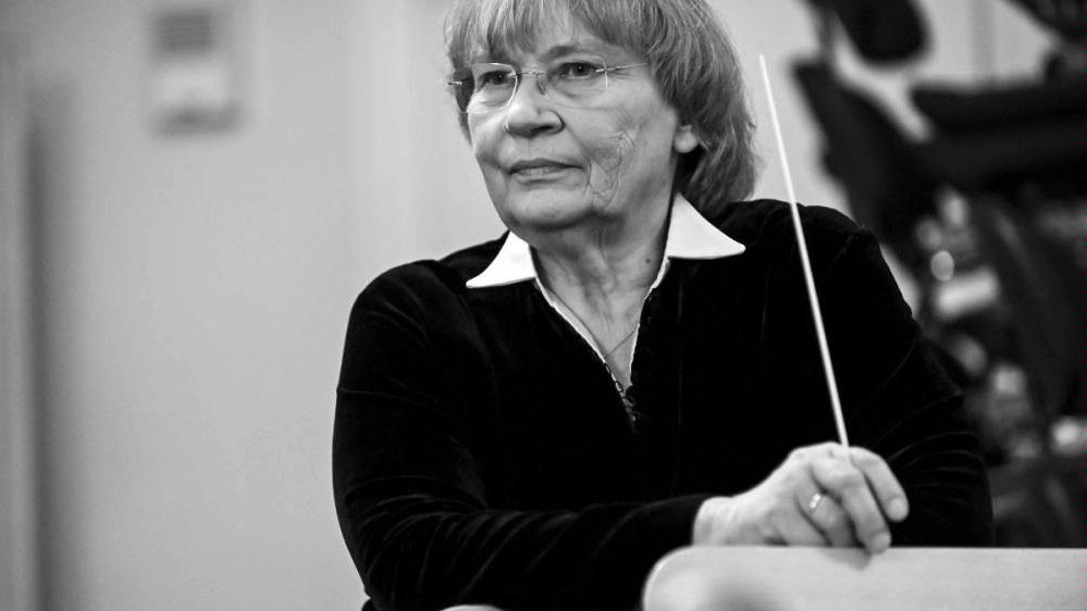 Black and white photo of the conductor Agnieszka Duczmal. The woman is holding a baton in her hand.and looking into the distance