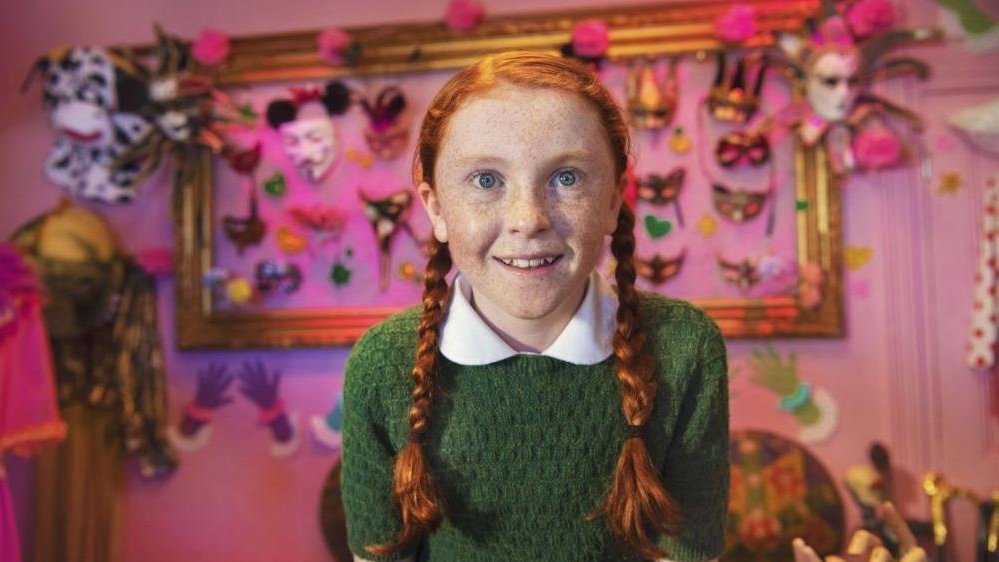 A picture of a smiling red-haired girl who is looking at the camera