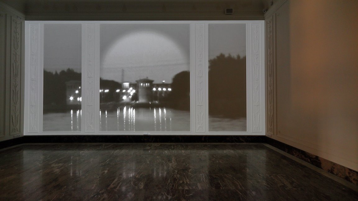 A photo from the exhibition: black and white picture of buildings and trees by the water