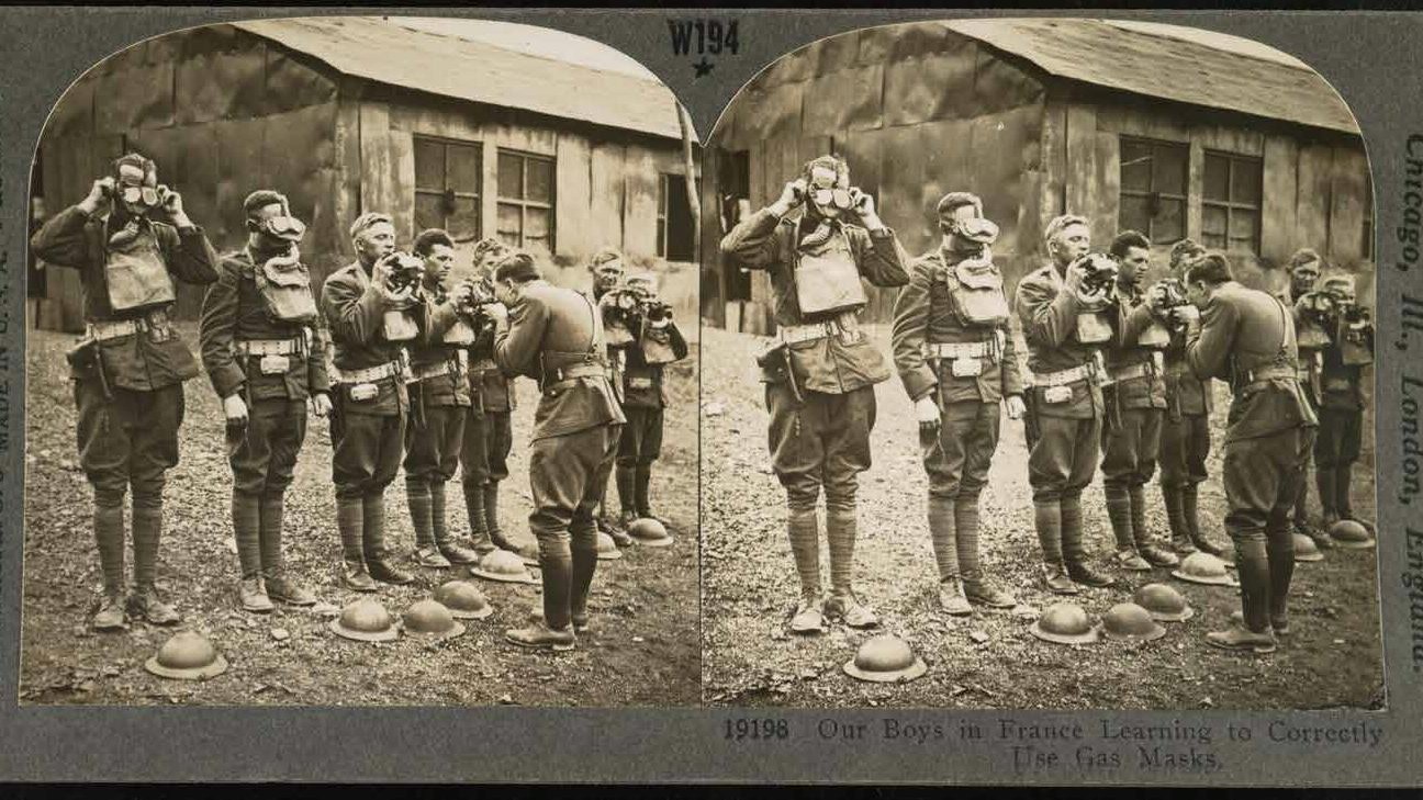 Photo in sepia colours of soldiers learning to use gas masks correctly.