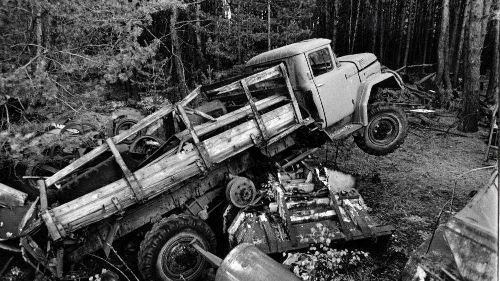 Black and white photo of a destroyed truck in the forest