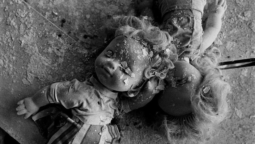 Black and white photo of two dolls covered with plaster.