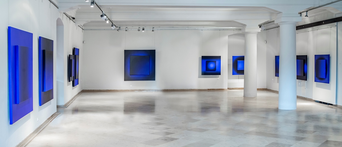 A bright room with white walls and square pictures on them in blue colours - grafika artykułu