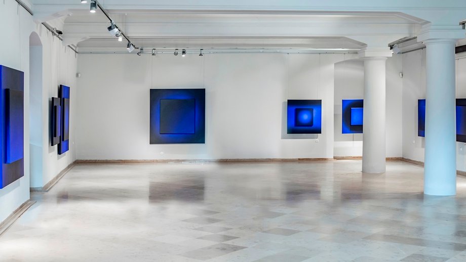 A bright room with white walls and square pictures on them in blue colours - grafika artykułu