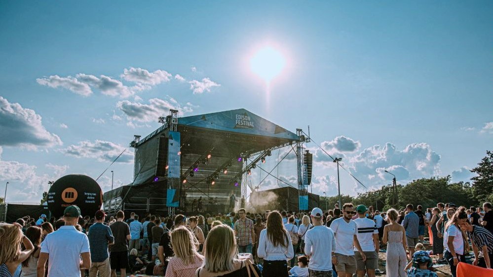 The photo shows the outdoor stage and the people standing in front of the stage. Summer day, looks like a hot day