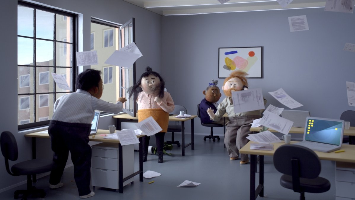 Picture from animated film: the room with open window, with 4 people in, who stand or sit by their desks. Because of wind some sheets of paper are floating in the air.