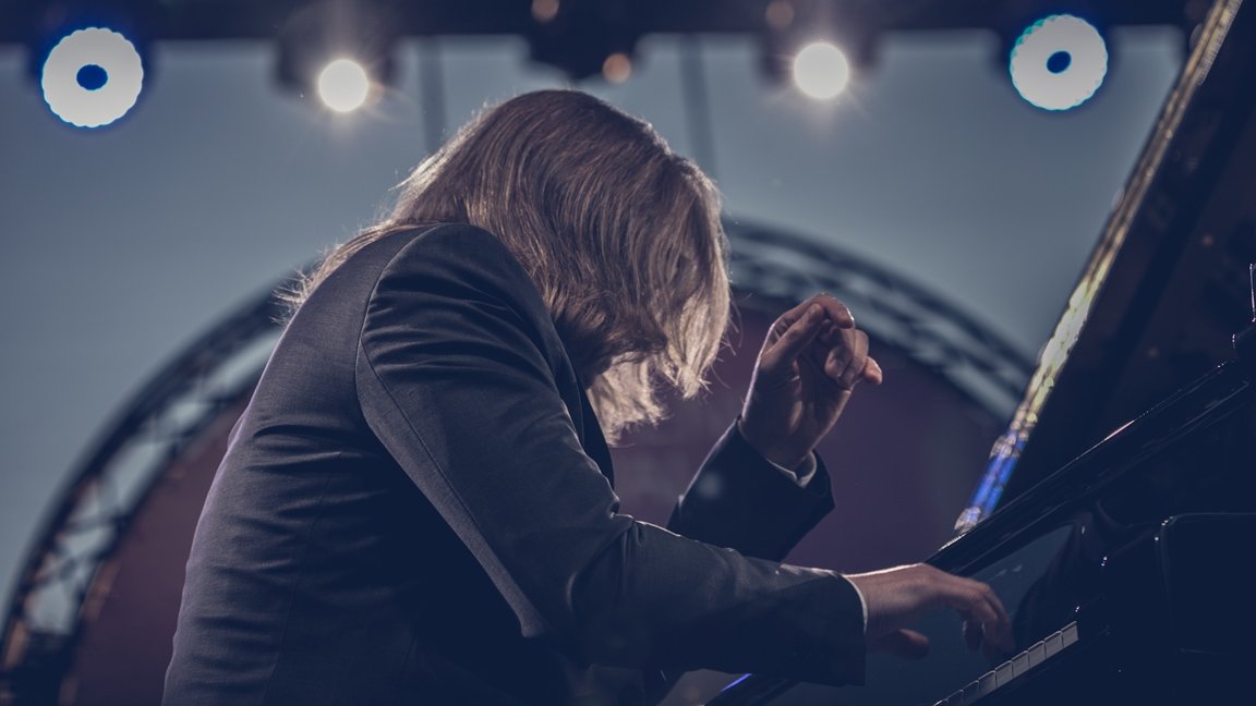 Leszek Możdżer playing piano on an open-air stage