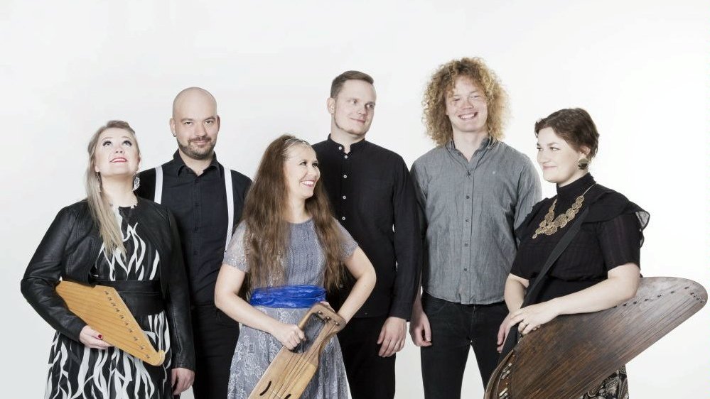 Photo of the band - three women and three men, three people hold their musical instruments. White background.