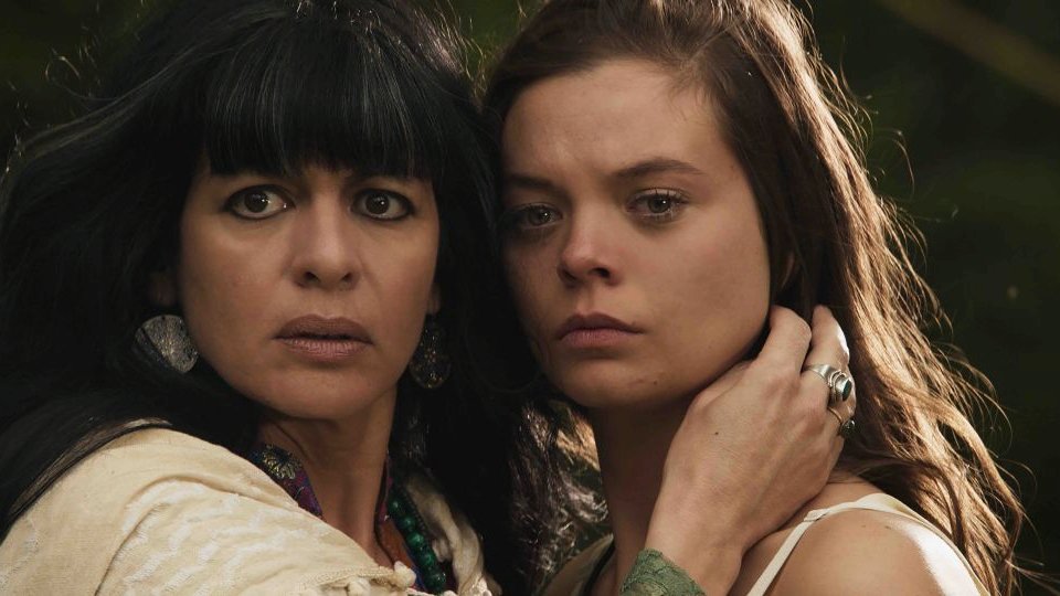 Photo from the movie: a woman and a teenage girl, who are standing close to each other, touching each other with their heads and looking at something. A woman is touching girl's neck with her hand.