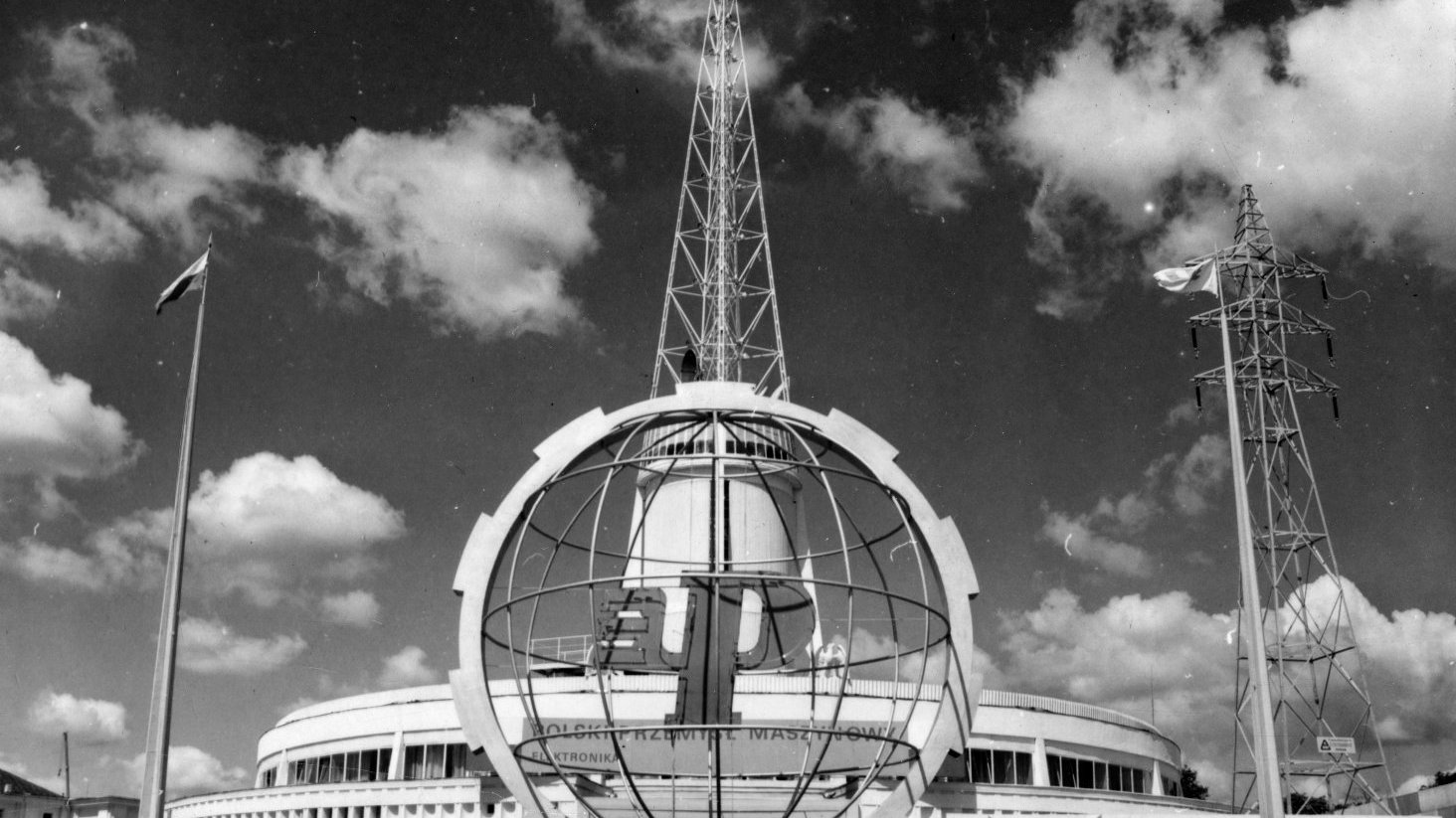 Black and white photo of a fair building - a spire which is a symbol of Poznań fair. In a foreground a sphere bearing the fair logo. - grafika artykułu