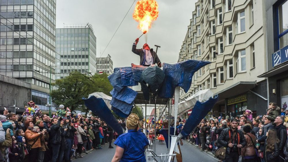 Photo from previous St. Martin parade: picture of St. Martin street with performers and people watching the show on left and right side of the street. Buildings in the background. - grafika artykułu