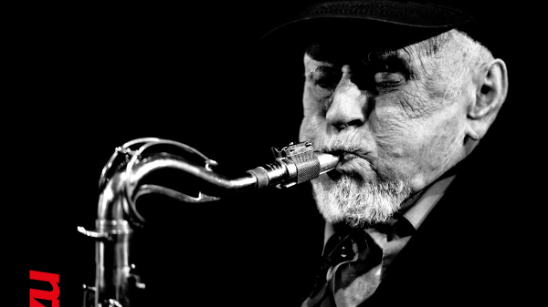 Concert poster - black and white photo of the artist on black background. At the top of the poster - information about the concert.