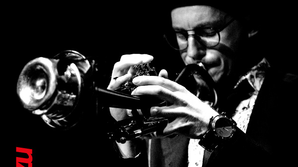 Concert poster - black and white photo of the artist on black background. At the top of the poster - information about the concert.