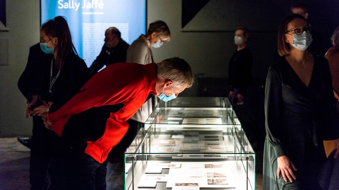 Photo of exhibition visitors - several people watching the exhibits.