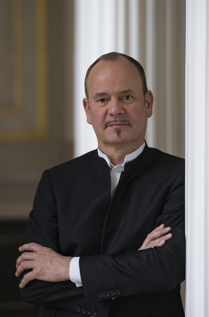 Photo of the conduktor Frank Strobel - a man in a suit with his arms folded - grafika artykułu