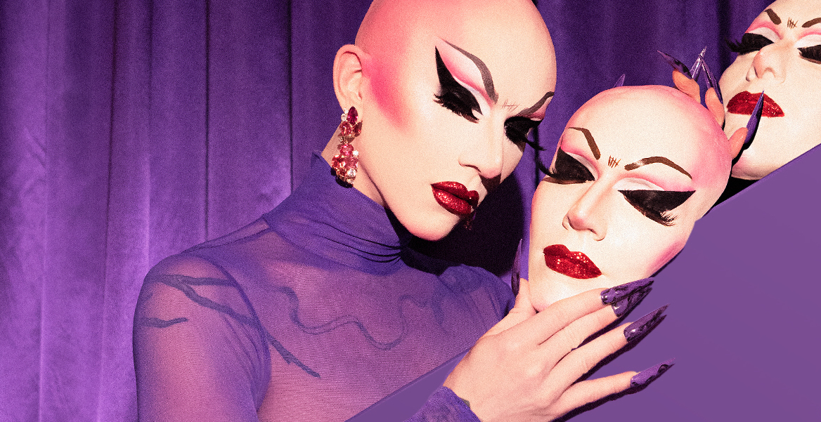 Picture of Sasha Velour with her bald head and with very intense make-up. She holds a mask in her hands. The violet background. - grafika artykułu