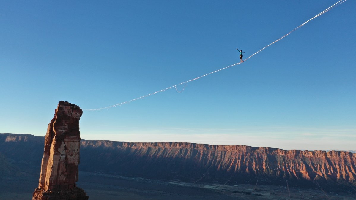Photo from the movie - a person walking a line between two rock towers.