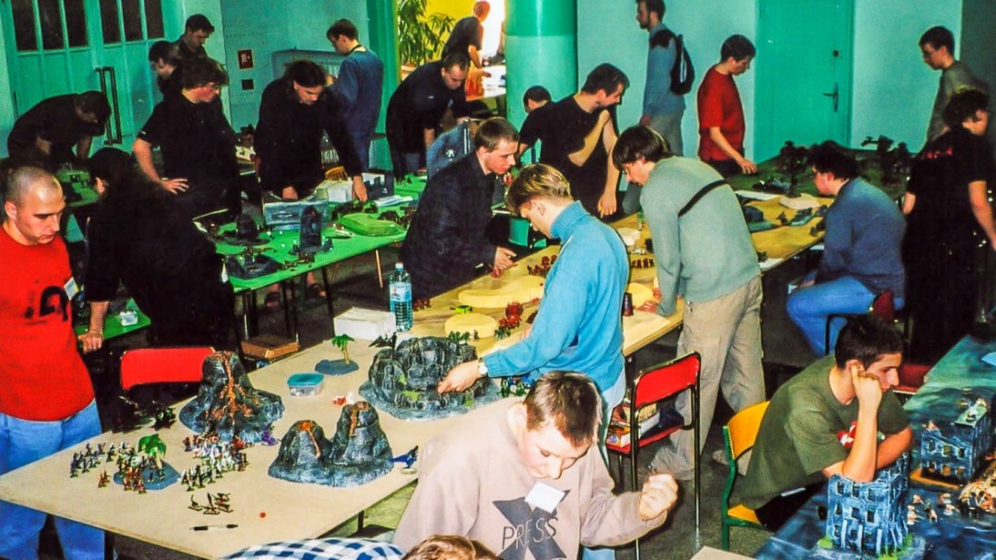 A room in which a dozen or so people are watching various mock-ups placed on tables.