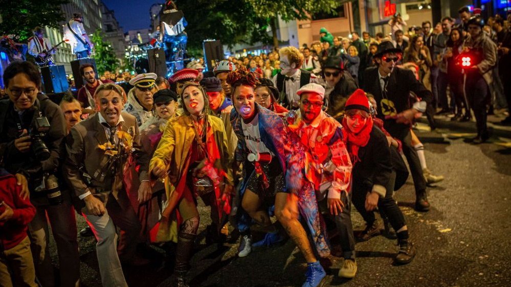 A scene from a performance - people in disguise on a street.